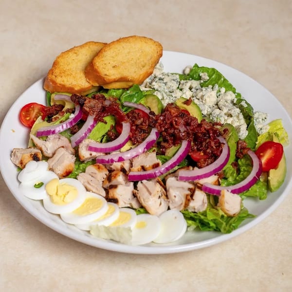 Cobb salad with grilled chicken, bacon, avocado, blue cheese, red onion, tomatoes, and hard-boiled eggs.