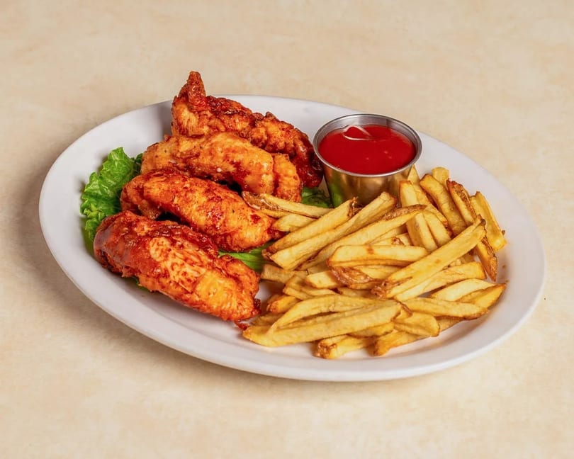 Crispy chicken tenders with a side of golden french fries and a cup of ketchup.
